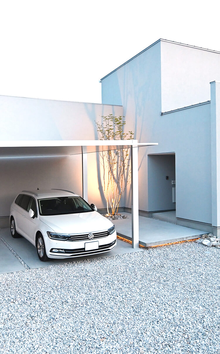 ミニマルな白い外観に調和したカーポート付き外構デザイン。駐車スペースと植栽を整えたエクステリア施工例。